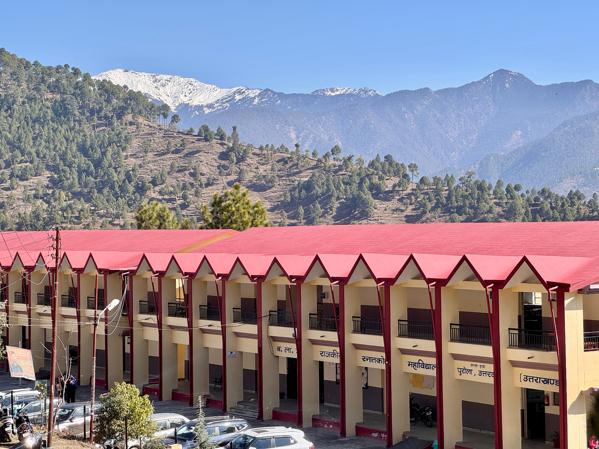 College building with snow-capped Himalayan mountains backdrop, Purola